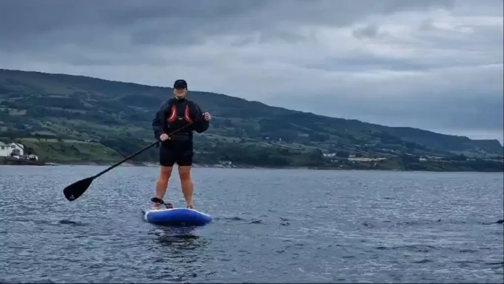 A woman standing on a paddle board on a cloudy day