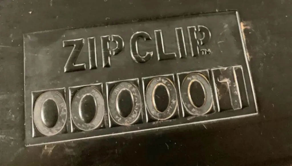A black surface with raised text reading ZIP CLIP above a series of embossed numbers: 000001.